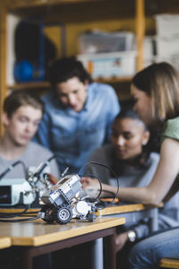 Toy car on desk against multi-ethnic students and teacher discussing in classroom at high school