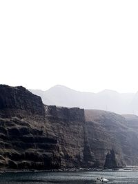 Scenic view of sea and mountains against clear sky