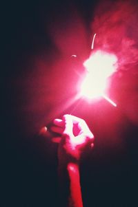 Close-up of hand holding illuminated red light