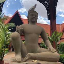 Statue against temple and building against sky