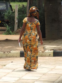 Rear view of african woman standing on footpath