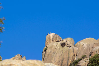 Low angle view of rocks against clear blue sky