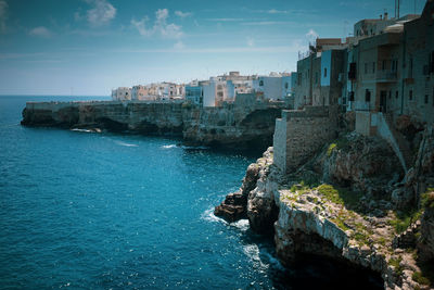 Buildings by sea against sky