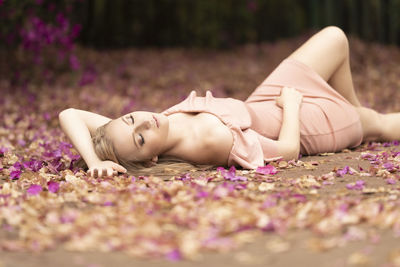 Woman lying on road amidst petals