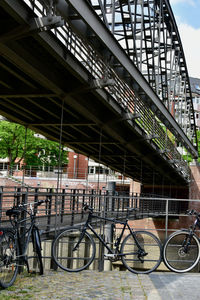 Bicycle parked against bridge in city