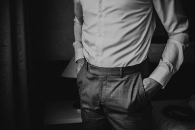 Midsection of man standing with hands in pockets