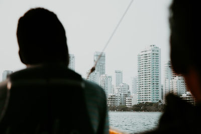 Rear view of man and buildings against sky in city