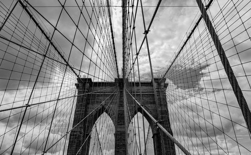 Low angle view of suspension bridge against cloudy sky