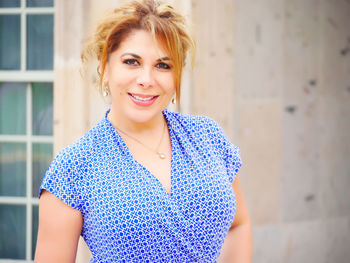 Close-up portrait of smiling mature woman against house