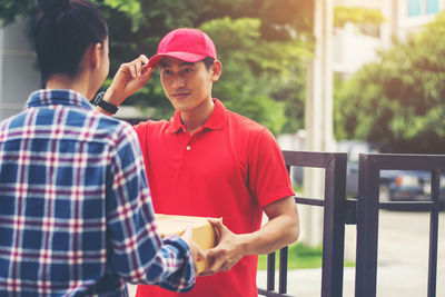 Man delivering package to female customer at gate