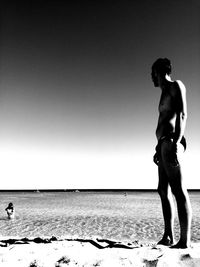 Man standing on beach against clear sky