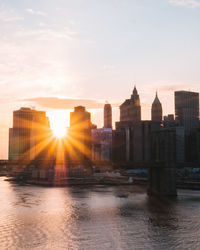 River in city against sky during sunset