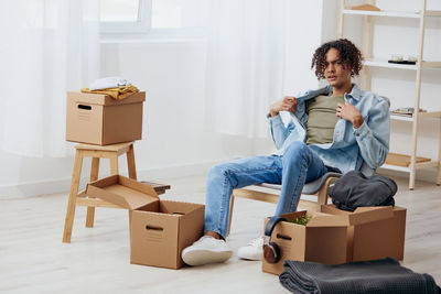 Portrait of young man sitting with boxes at home