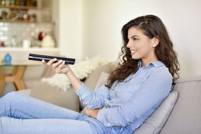 Portrait of smiling woman sitting on sofa at home