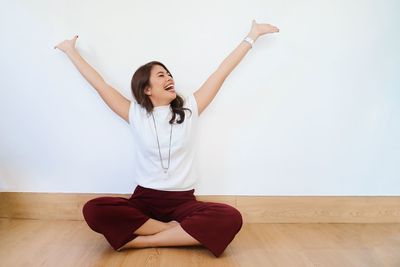 Full length of young woman against white wall