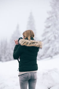 Rear view of woman standing on snow covered landscape