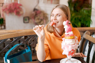 Beautiful woman eats dessert in form pink flamingo in cafe. time for fun, vows