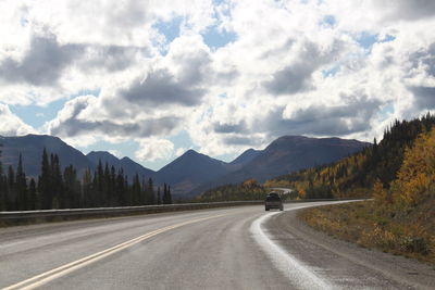 Cars on road by mountains against sky