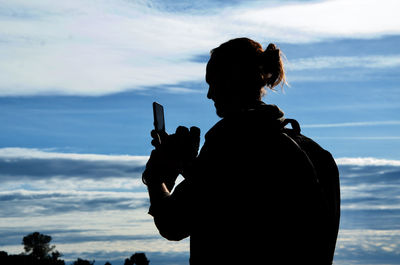 Rear view of silhouette person photographing against sky