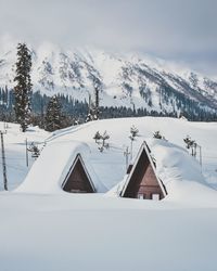 Snow covered houses against mountains and sky