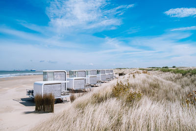 Modern beach huts at sea shore against sky