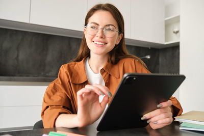 Portrait of young woman using digital tablet while sitting at office