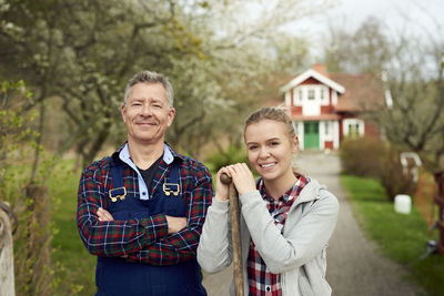 Portrait of confident farmer standing with daughter on footpath