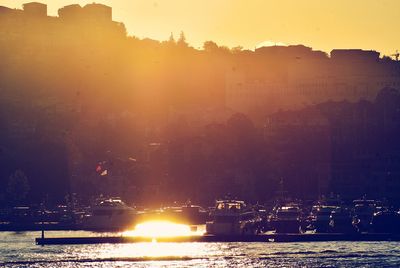 River by cityscape against clear sky during sunset