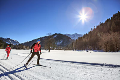 People skiing on snowy field against sky