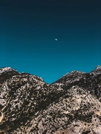 Low angle view of mountain against clear blue sky