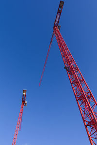 Low angle view of crane against clear blue sky
