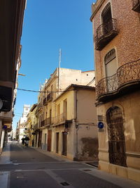 Street amidst buildings against clear blue sky
