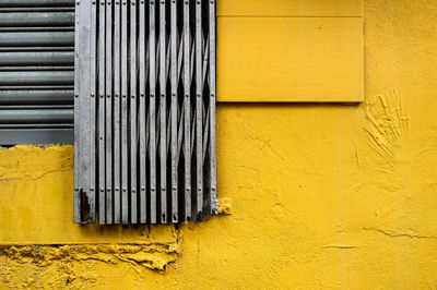 Close-up of security metal door against yellow wall