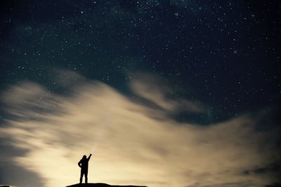 Silhouette person with flashlight standing against star field