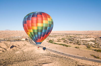 Hot air balloons in desert against clear blue sky
