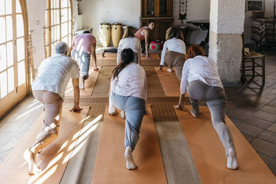 Friends learning exercise from instructor in yoga studio