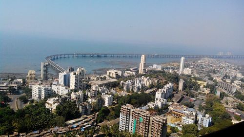 High angle view of city by sea against clear sky