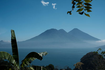 Scenic view of sea and mountains against blue sky