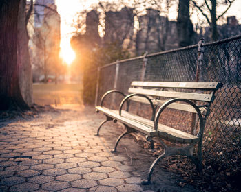 Empty bench in park during sunset