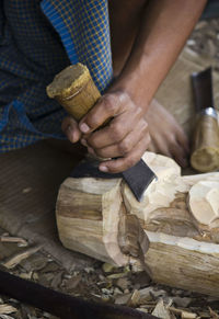 Low section of man carving wood in workshop
