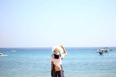 Rear view of woman by sea against clear sky