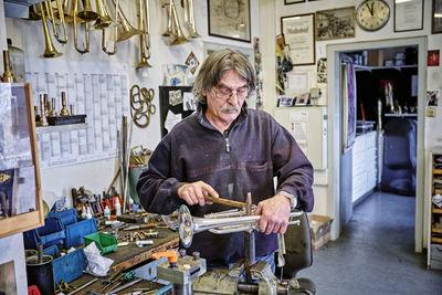 Instrument maker repairing trumpet in workshop