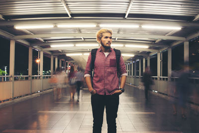 Young man standing on footbridge at night