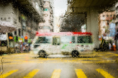 Cars on street seen through wet glass window