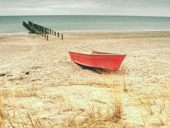 Deck chairs on beach against sky