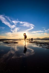 Man standing on beach against sky during sunset