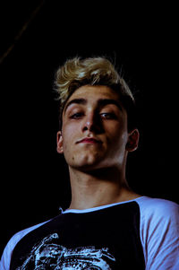 Portrait of young man against black background