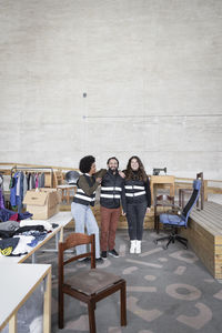 Happy male and female workers standing amidst goods at recycling center