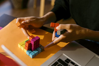 Hands of businesswoman playing with toy blocks by laptop at home