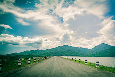 Road leading towards mountains against sky